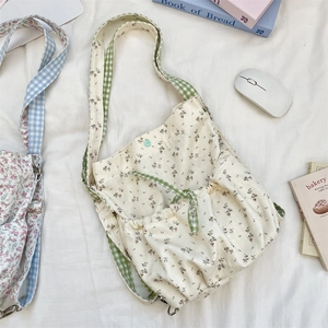 Detailed close-up of floral canvas tote bag with green gingham straps and side pocket