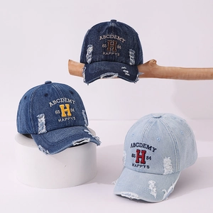 Detailed view of distressed denim baseball caps with vintage embroidery and torn edges