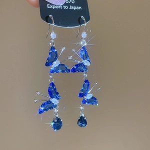 Close-up of blue zircon butterfly earrings with teardrop pendant and starburst sparkles