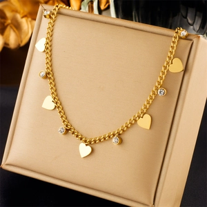 Detail of golden heart and crystal pendants on a classic Cuban link chain necklace