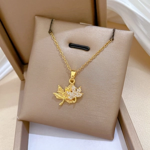 Detailed view of gold double maple leaf pendant with sparkling zircon in a jewelry box