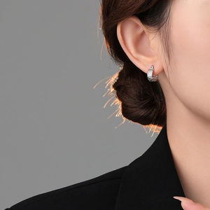 Close-up of silver hoop earrings with irregular lava texture and metallic finish