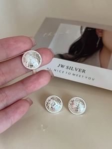 Detailed view of handmade textured silver ring and stud earrings with rope bezel edge