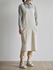Close-up of minimalist beige linen apron featuring two large functional front pockets