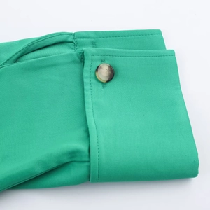 Close-up of green satin shirt cuff featuring a brown marble texture button detail