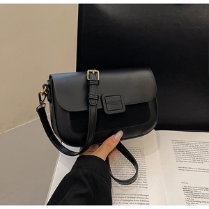 Detail of black flap shoulder bag featuring mixed leather textures and golden hardware