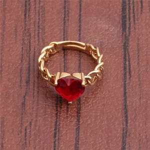 Macro detail of red heart-shaped gemstone ring with gold-plated woven band texture