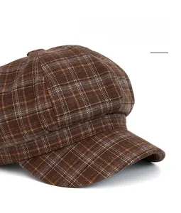 Detail of a brown plaid newsboy cap featuring a wide, flexible and foldable brim