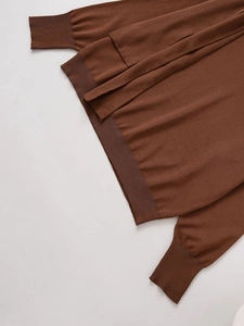Detailed macro shot of rust red knit sweater ribbed hem and sleeve cuffs texture