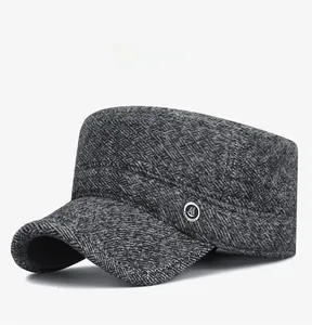 Detail of dark grey herringbone flat cap with metallic anchor badge and stitching