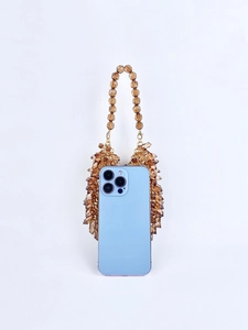 Macro shot of amber acrylic beads and golden chain attached to a smartphone case