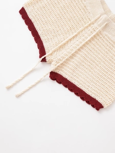 Detail of beige crochet knit shorts with burgundy wave hem and drawstring waist