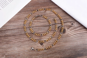 Detail of silver and gold toned curb chain necklace and bracelet set on wood