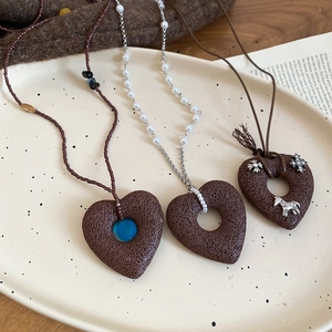 Macro detail of retro necklaces with stone heart pendants and pearls in a ceramic bowl