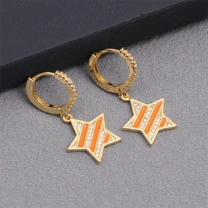 Detail of gold hoop earrings with orange enamel star pendants and cubic zirconia stones