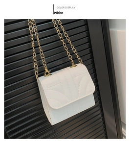 Close-up of white quilted mini square bag with golden chain strap on dark background