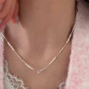 Detail of silver bow pearl necklace with a sparkling diamond pendant on a model