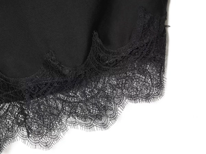 Detail of elegant black satin fabric featuring intricate eyelash lace trim and texture