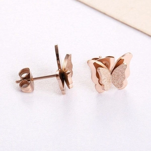 Detail view of double-layered butterfly studs with matte and polished rose gold finishes