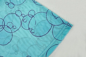 Macro detail of blue mesh dress with character print and high-quality edge stitching