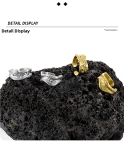 Close-up of S925 silver and matte gold irregular rings with zircons on black stone