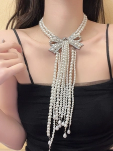 Macro detail of bridal pearl choker with rhinestone bow and long layered tassels