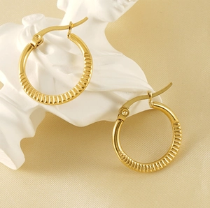 Detail of 18K gold plated hoop earrings with vertical stripe texture on beige silk