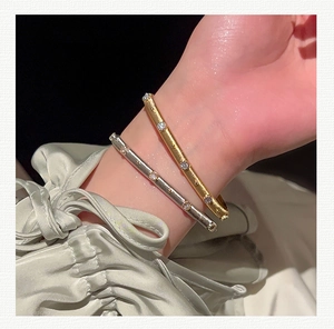 Detail of gold and silver brushed metal bracelets with zircon accents on model