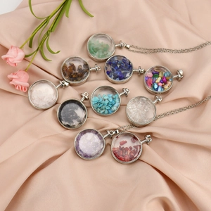 Round silver necklace with colorful natural crushed stones on soft pink silk fabric
