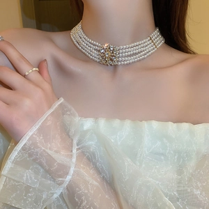 Detail of a multi-layer pearl choker with rhinestone flower and gold base on a model