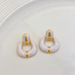 Detail of French vintage gold-plated earrings with white marble enamel on ceramic plate
