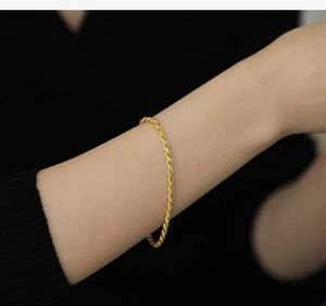 Detailed close-up of a delicate golden rope chain bracelet worn on a female wrist