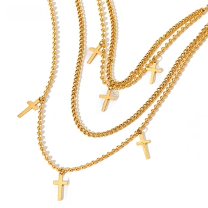 Detail of layered gold stainless steel beaded chains with multiple cross pendants