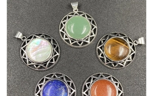 Detail of five round silver pendant charms with diverse natural gemstones on black background