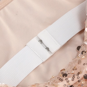 Detail of off-shoulder sequin dress showing elastic band with metal hook and pearl accents