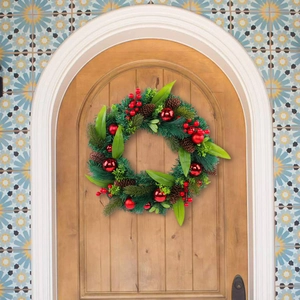 Christmas wreath with pine needles, red berries and pine cones on a wooden door