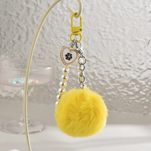 Détail d'un porte-clés perlé à la main avec pompon jaune, perles et pendentif coeur