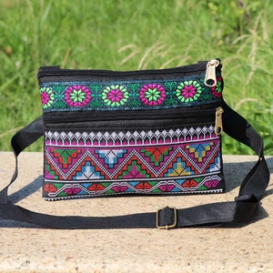 Detail of colorful geometric floral embroidery on a black ethnic style crossbody bag