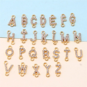 Macro view of 26 gold alloy alphabet pendants with rhinestones on a dual-tone background