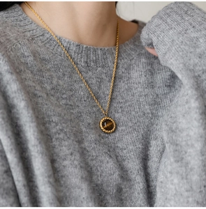Close-up of a vintage golden twist chain necklace with a tiger eye stone pendant