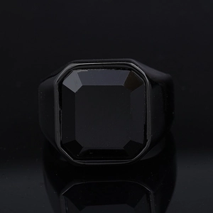 Close-up of men's black signet ring with an octagonal black gemstone on dark background