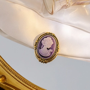 Close-up of vintage cameo brooch with purple base and white relief on silk fabric