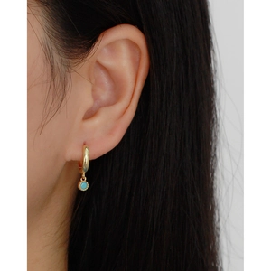 Detailed view of s925 gold hoop earring with a turquoise pendant on woman's ear