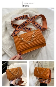 Detail of brown quilted crossbody bag with golden chain and patterned wide fabric strap