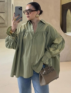 Close-up of olive green oversized cotton shirt with pleated cuffs and loose silhouette