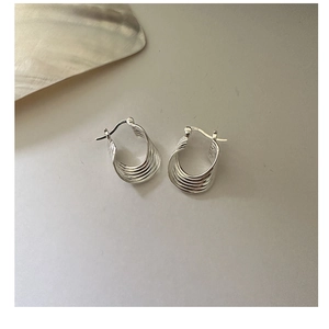 Detailopname van meerlaagse gebogen S925 sterling zilveren oorringen met zilvermerkje