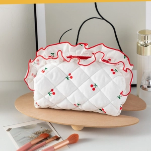 Vue détaillée de la trousse de maquillage à fleurs et cerises avec bord festonné