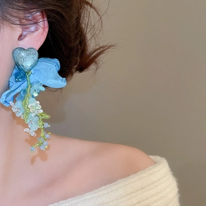 Close-up of elegant floral heart earrings with long crystal tassels on a model