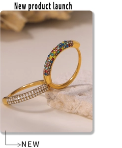Detail of gold-plated rings featuring colorful zircons and white crystals on a stone