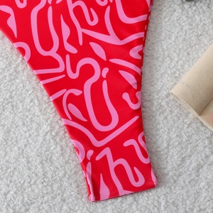 Detailed close-up of red and pink bikini side ties with abstract print on plush fabric